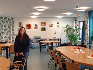 Feierwerk_Blog_Nachbarschaftstreff_NBT_Sylvie_allein_im_Gruppenraum_Hintergrund_Eingang_Treppenhaus